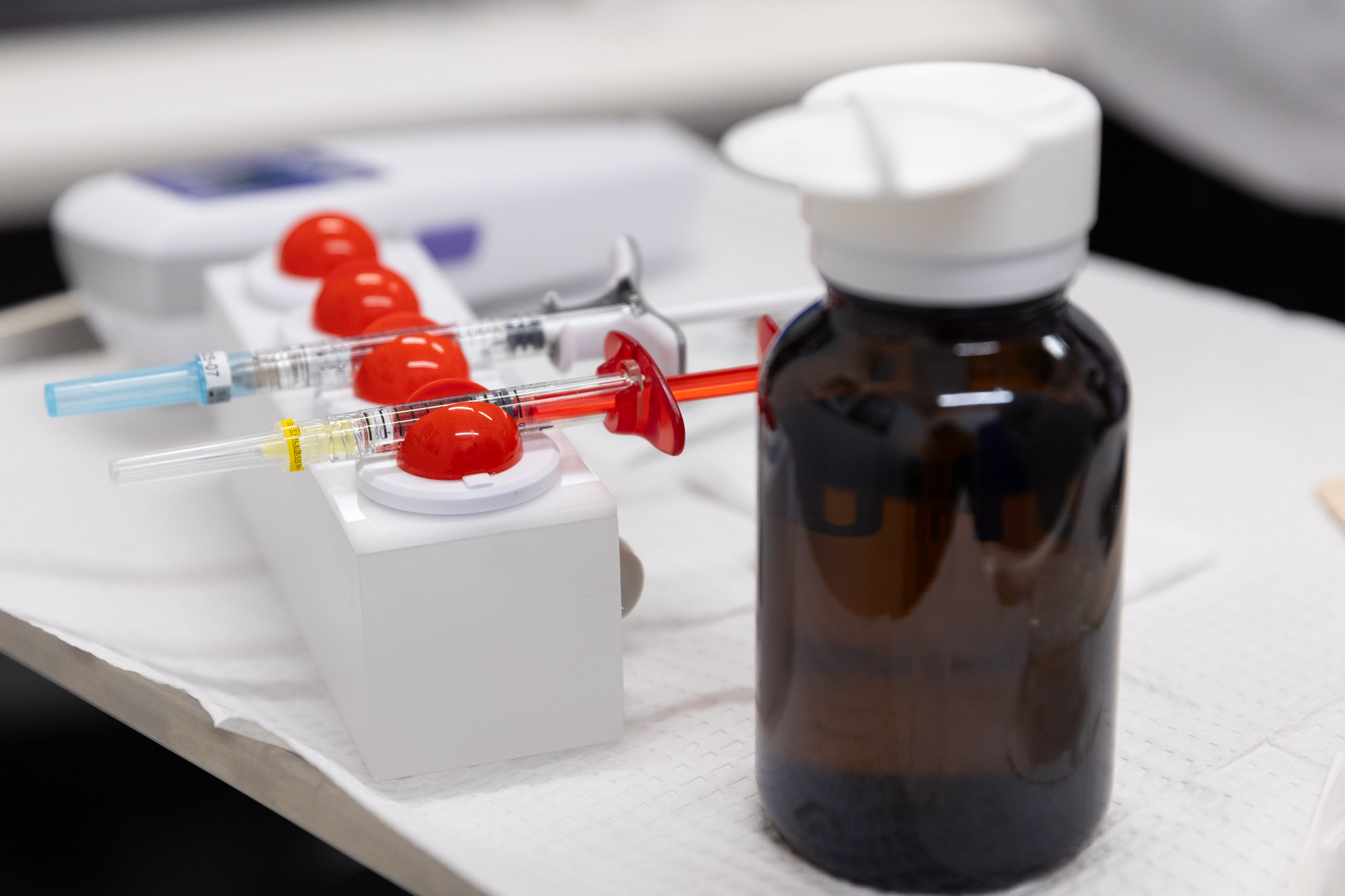 A bottle of filler with needles next to it