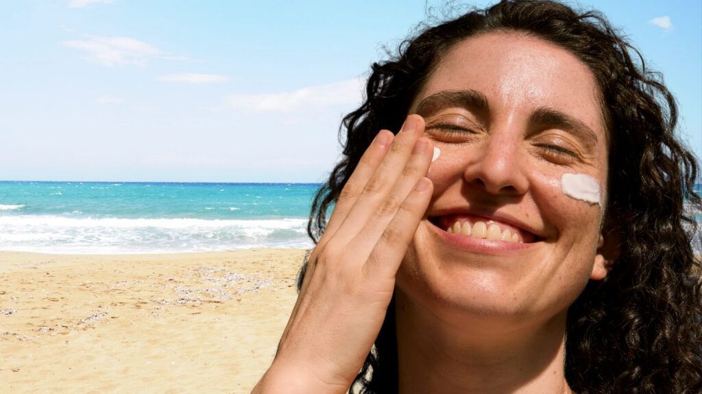 Women rubbing lotion on her face at the beach