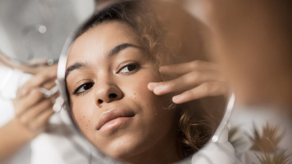 Woman looking at skin in mirror