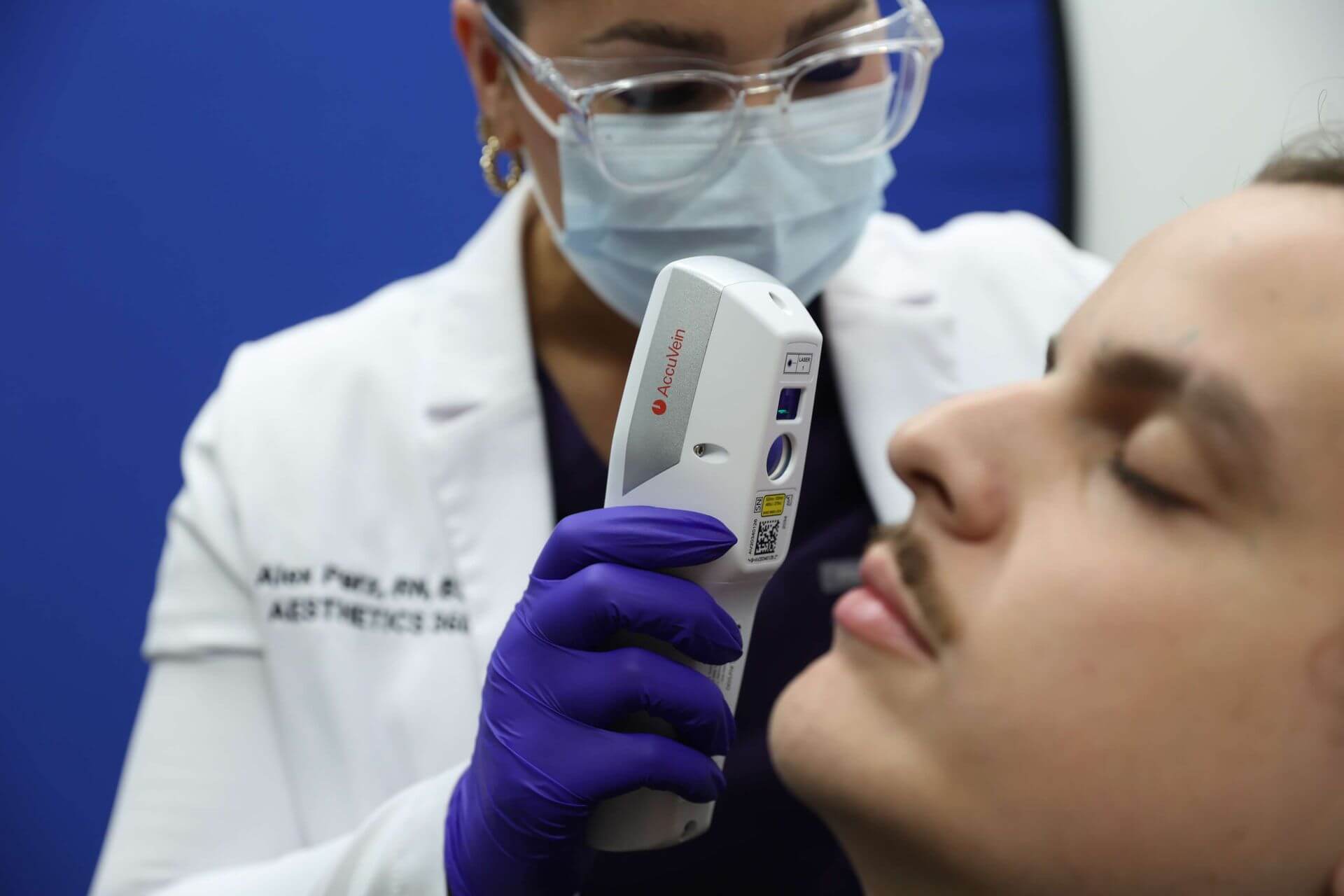 worker using a vein finder on patient's face