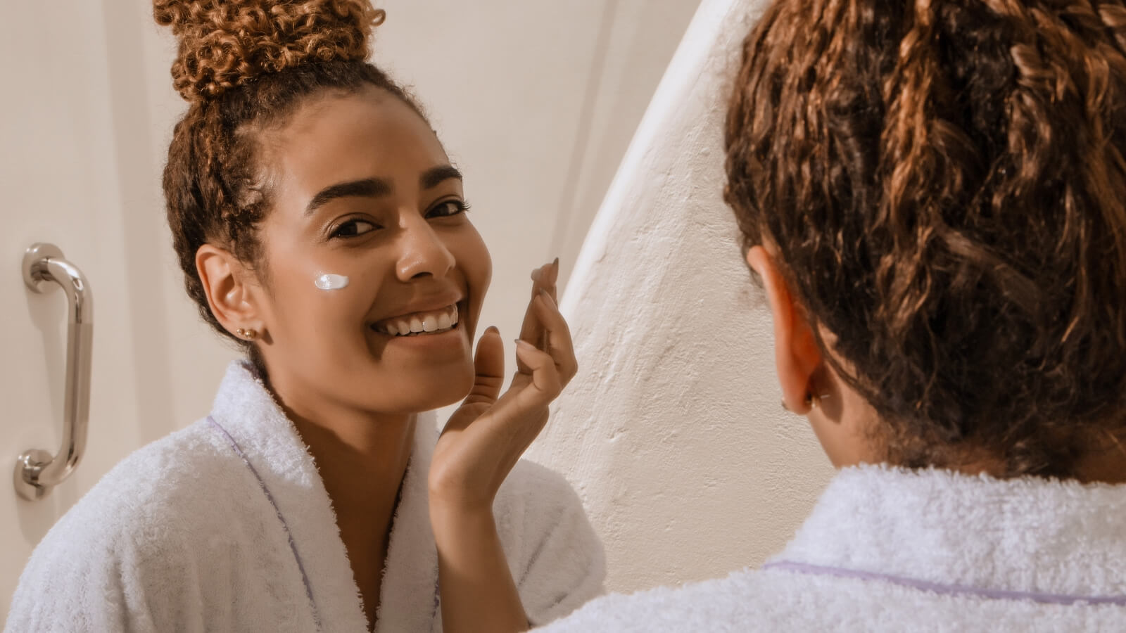 image of woman adding sunscreen to her face
